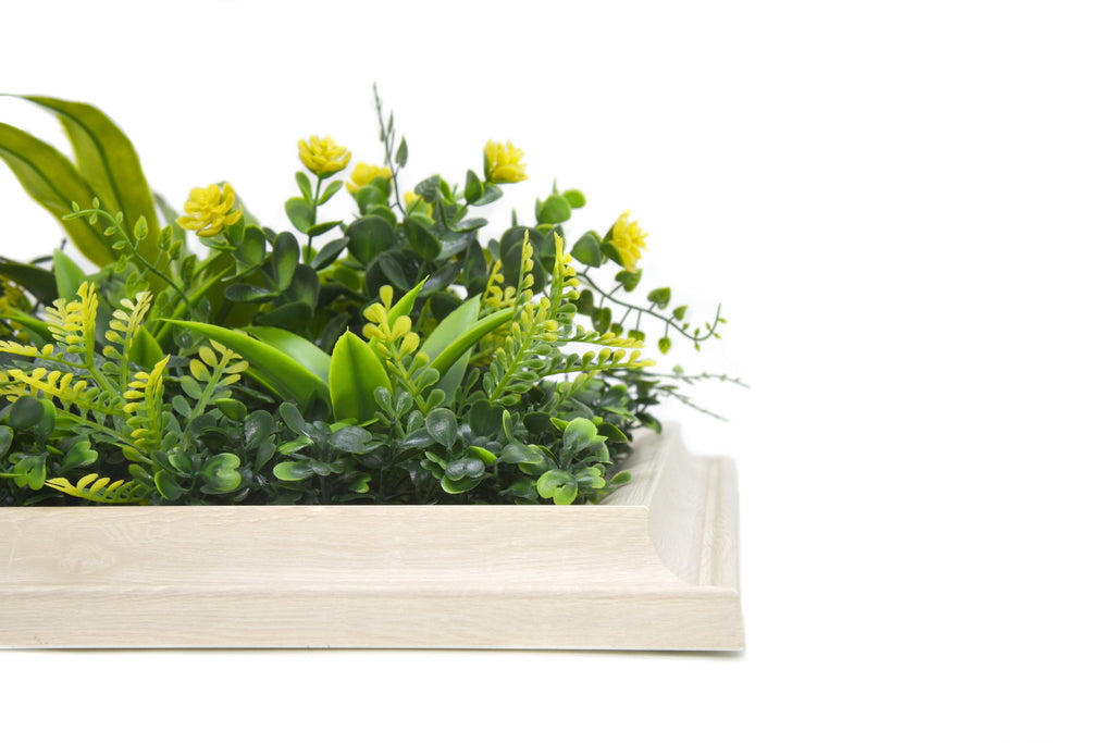 Artificial greenery in a white rectangular container on a white background
