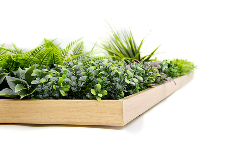 Artificial green plants in a wooden planter on a white background